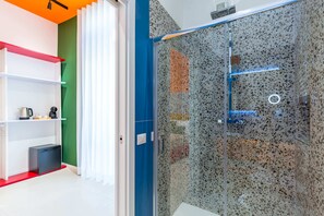 A modern bathroom with a glass shower enclosure, a white sink, and a small black cabinet. - Starguest Duomo  (Naples)