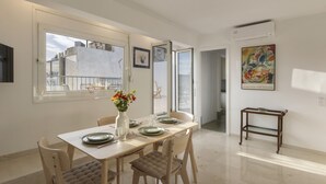 A dining area with a table set for four, a vase with flowers, and a painting on the wall. - Central Athenian Penthouse Acropolis (Athens)