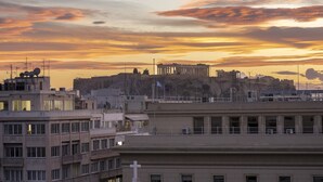 A cityscape with a prominent building featuring a red-tiled roof and classical architecture. - Central Athenian Penthouse Acropolis (Athens)