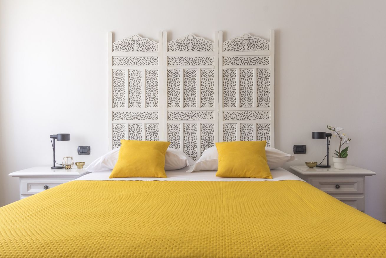 A neatly arranged bedroom with a bed, two bedside tables, and a decorative headboard.