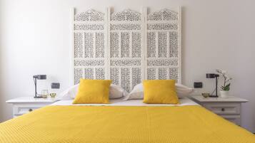 A neatly arranged bedroom with a bed, two bedside tables, and a decorative headboard.