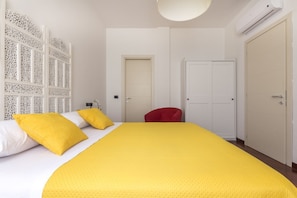 A bedroom with a bed, a red chair, and a white wardrobe. - Casa Margarita, elegant house with parking (Firenze)