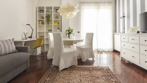 Un salon moderne comprenant un canapé, une table à manger avec des chaises, une bibliothèque et un radiateur.