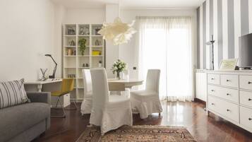 Un soggiorno moderno con divano, tavolo da pranzo con sedie, libreria e termosifone.