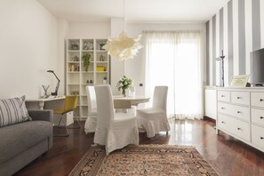 Un salon moderne comprenant un canapé, une table à manger avec des chaises, une bibliothèque et un radiateur.