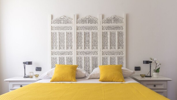 A neatly arranged bedroom with a bed, two bedside tables, and a decorative headboard. - Casa Margarita, elegant house with parking (Firenze)