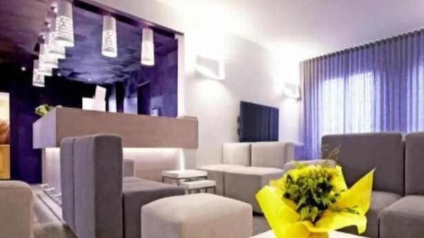 A modern hotel lobby with grey sofas, a white coffee table, and a yellow flower arrangement. - Kyriad Direct Valence Nord Bourg Les Valence (Bourg-les-Valence)