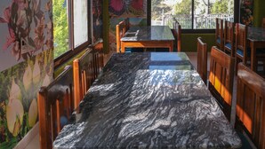 A restaurant with marble-top tables and wooden chairs. - The White Rain Hotel (Lansdowne)