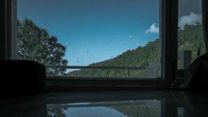 A window with a view of a forested hillside and a clear sky. - The White Rain Hotel (Lansdowne)