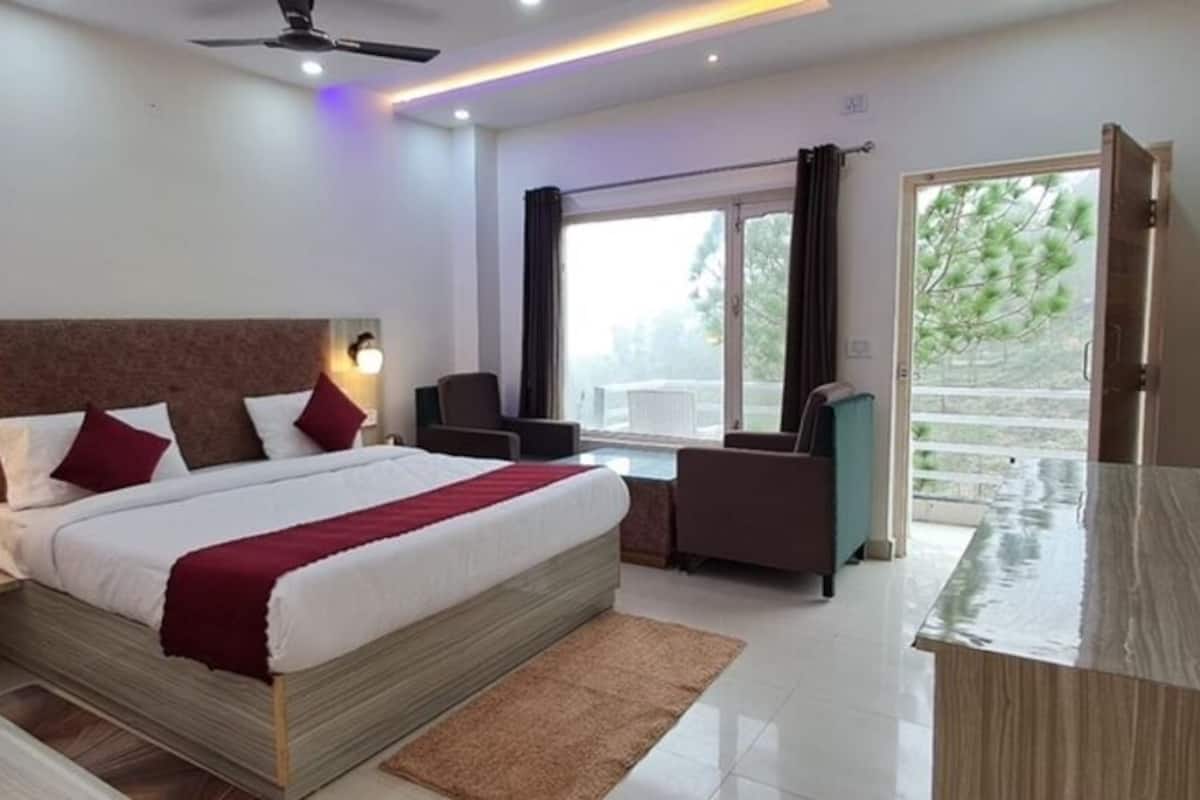 Habitación de hotel moderna con una cama grande, un escritorio, una silla y vistas al exterior.