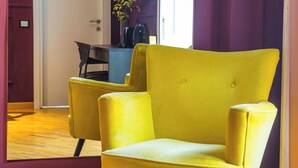 A yellow armchair in a room with wooden flooring and purple walls. - Starguest Dante  (Naples)