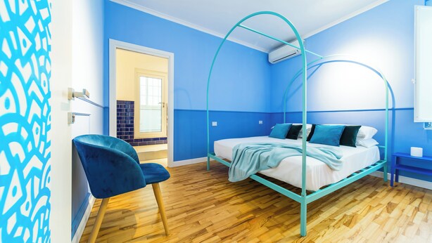 A room with a bed, a chair, and a door. - Starguest Dante  (Naples)