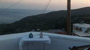 Une table recouverte d’une nappe blanche, installée sur un toit, d’où l’on peut admirer un paysage côtier avec des collines et une étendue d’eau.