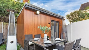 A wooden outdoor dining area with a table and chairs, a potted plant, and a grill. - Spacious 4BR Home in Brentford, Free Parking (Brentford)