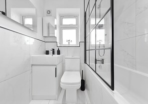 Ein modernes Badezimmer mit Toilette, Waschbecken und Duschbereich.
