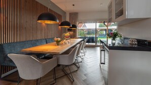 Eine moderne Küche mit einem Holztisch, weißen Stühlen und Pendelleuchten.