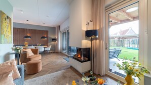 Ein modernes Wohnzimmer mit Kamin, bequemer Sitzgelegenheit und Blick ins Freie.