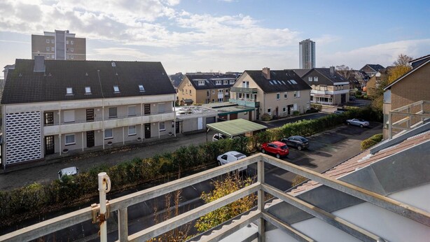 A residential area with multiple two-story houses, a parking lot, and a tall building in the background. - Ferienwohnung in Busum (Büsum)