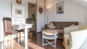 A modern living room with a dining area, a round coffee table, and a sofa. - Ferienwohnung in Busum (Büsum)
