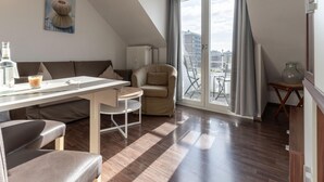 A modern living room with a dining area, a sofa, a chair, and a view of the city through large windows.