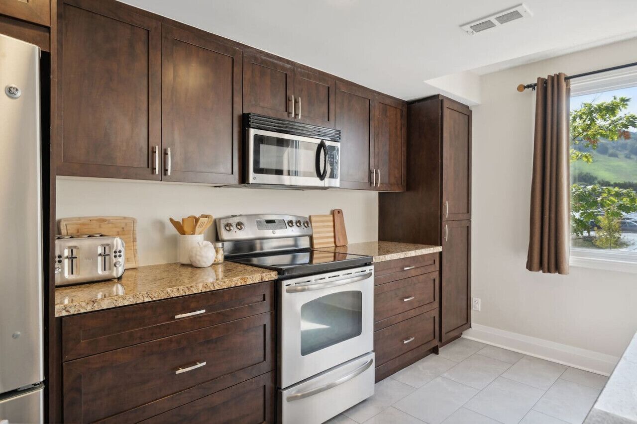 A kitchen with dark wooden cabinets, stainless steel appliances, and a granite countertop.