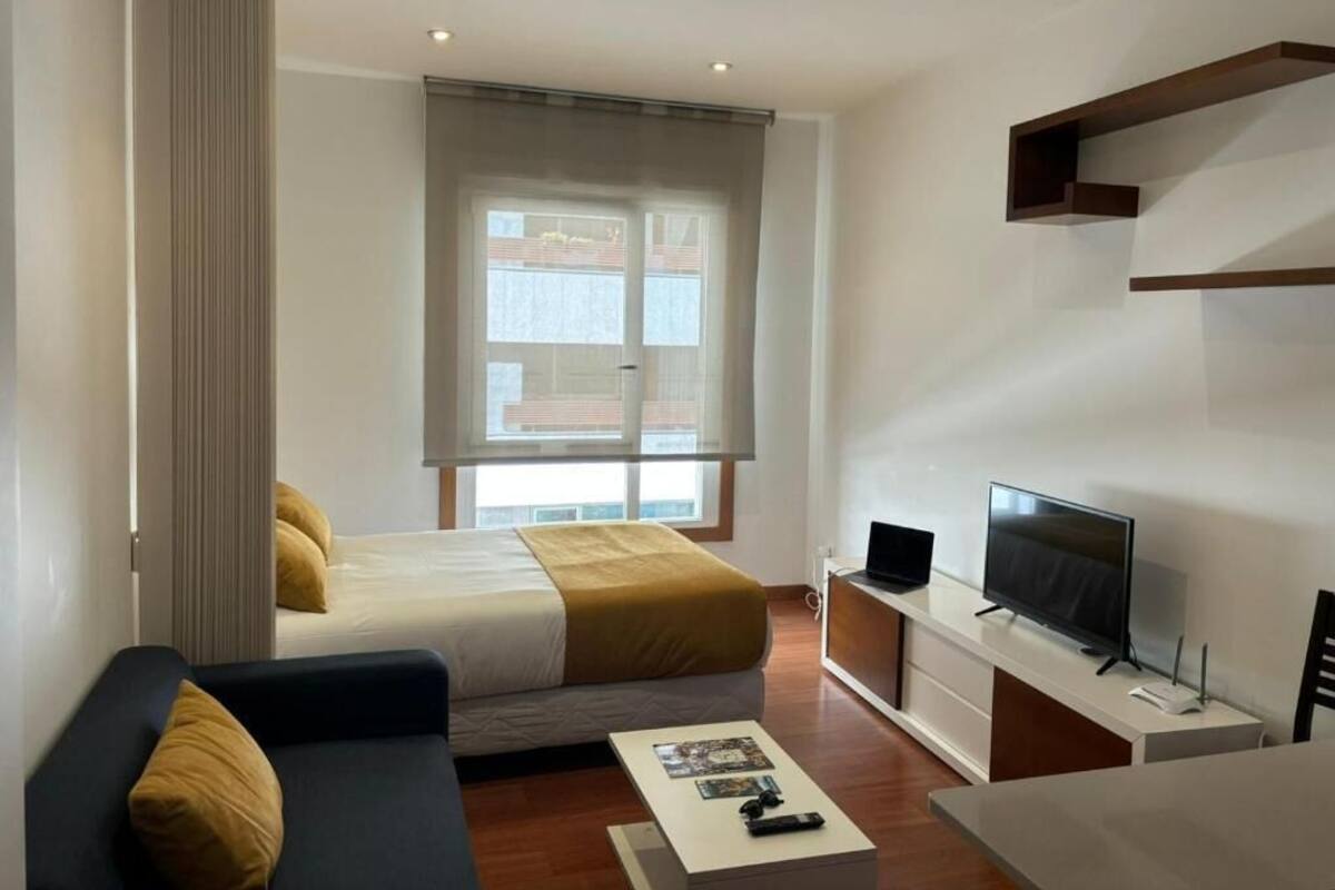 Une chambre d’hôtel moderne équipée d’un lit, d’un canapé, d’une télévision et d’une fenêtre avec des stores.