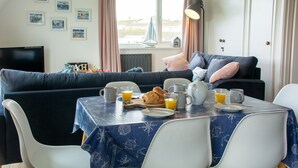 Angolo pranzo con tavolo apparecchiato per la colazione, divano e televisore.