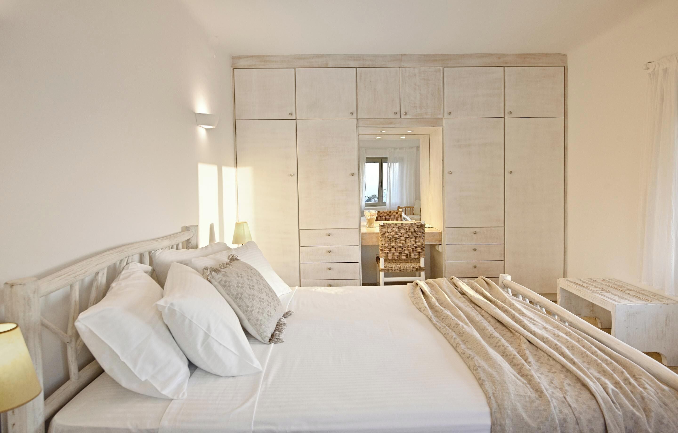 A bedroom with a large bed, a dresser, and a mirror.