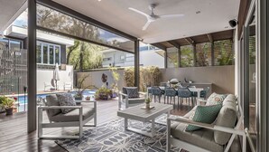 Ein moderner Außenbereich mit Pool, Sitzgelegenheiten und Deckenventilator.