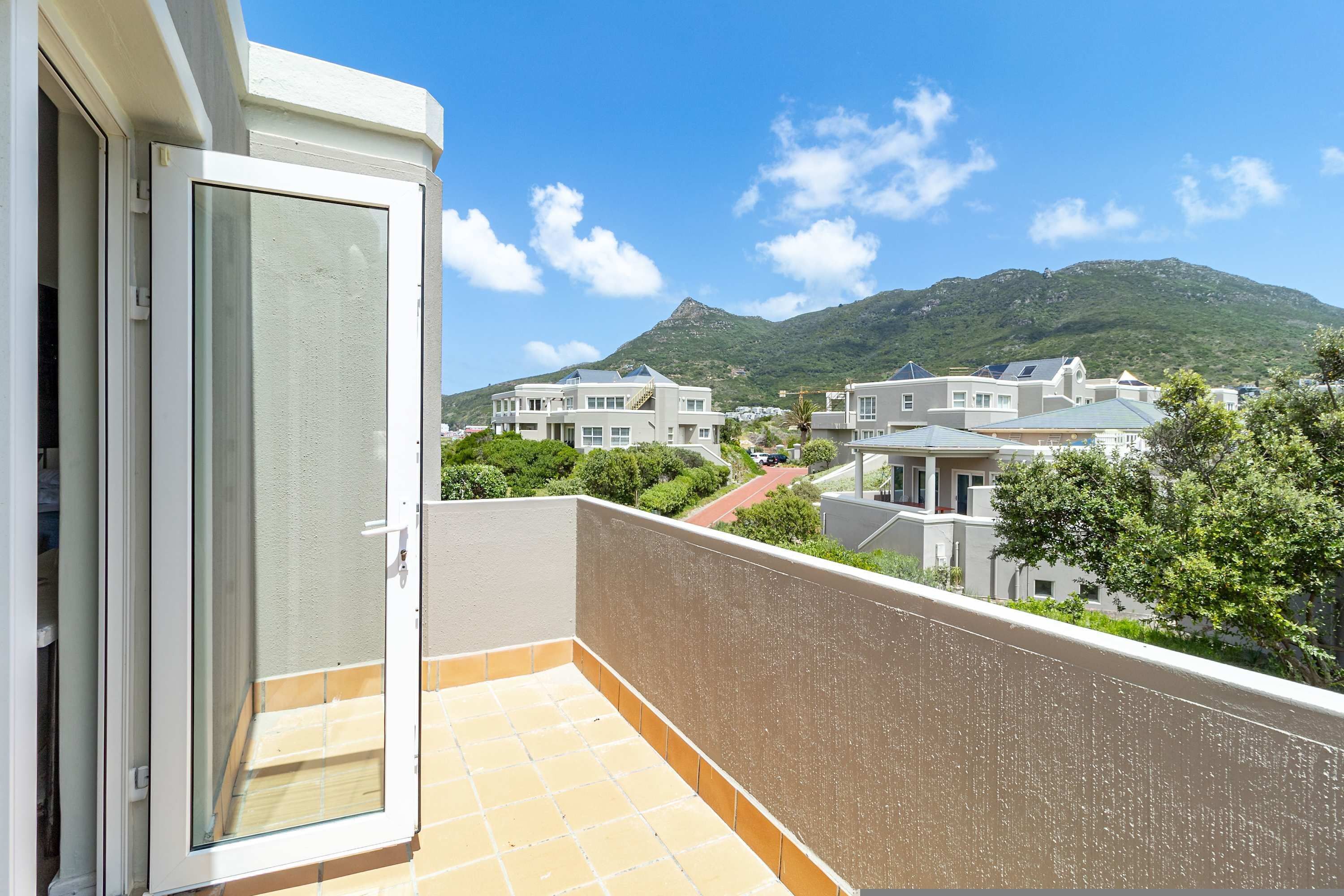 A balcony with a view of residential buildings and a mountain in the background.