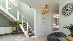 Una escalera con barandillas de vidrio que lleva a un dormitorio.