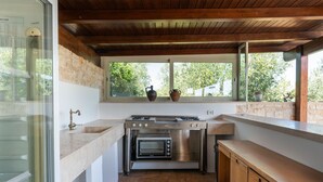 A compact kitchen with a stone wall, a window with a view, a built-in oven, and a sink.