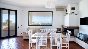 A dining area with a table and chairs, a sofa, a TV, and a fireplace.