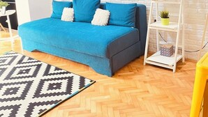 Una sala de estar moderna con un sofá azul, un tapete estampado, una pared de ladrillo blanco y un cuadro.