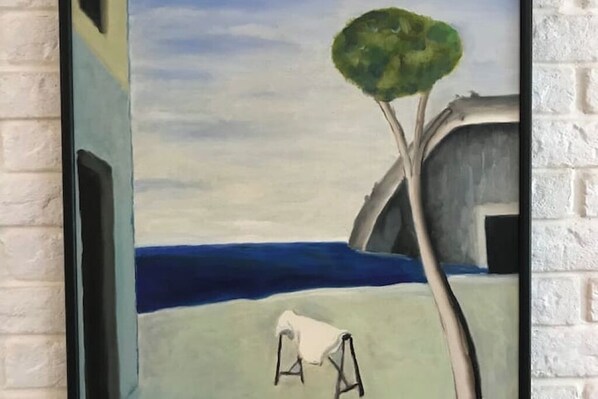 A painting of a tree and a chair by a body of water.