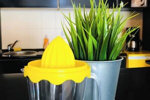 Un comptoir de cuisine avec un extracteur de jus jaune et une plante verte en pot.