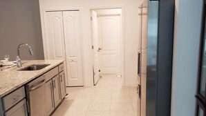 A kitchen with a stainless steel refrigerator, a sink with a faucet, and a countertop. - Home away from Home (Port St. Lucie)