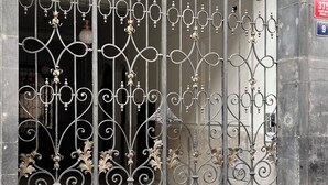 A wrought iron gate with intricate designs, a stone wall, and a cobblestone pavement. - Old Town - Aparthotel 28. Října (Prague)