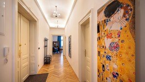 A hallway with wooden flooring, white doors, and a large painting on the right wall. - Old Town - Aparthotel 28. Října (Prague)