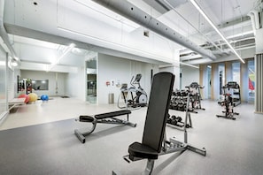 Uma academia moderna com diversos equipamentos de ginástica, incluindo esteiras, supino e pesos livres.