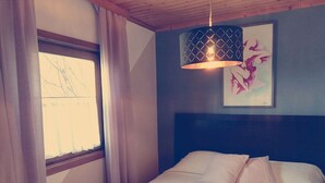 A bedroom with a bed, a window with curtains, a wall-mounted artwork, and a pendant light. - Die Labsalerie am Wörthersee - Apartment with 1 bedroom and lake view (Pörtschach am Wörthersee)