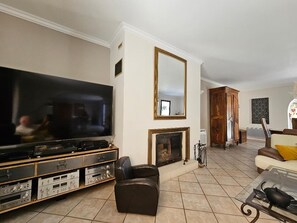 A living room with a large flat-screen TV, a fireplace, a wooden cabinet, and a sofa. - 200 m² Villa, Sleeps 8, 4 Bedrooms, Swimming Pool, Provence, Ventoux (Mazan)