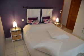 A hotel room with a large bed, two nightstands with lamps, and a wooden door. - 200 m² villa, sleeps 8, 4 bedrooms, pool, Provence, Ventoux (Mazan)