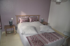 A bedroom with a bed, two bedside tables, a lamp, and a patterned bedspread.