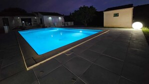 Une piscine rectangulaire entourée d’une terrasse carrelée.