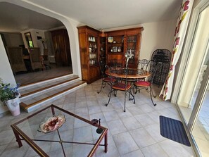 A dining area with a round table and chairs, a cabinet with glass doors, and a staircase leading to another room.