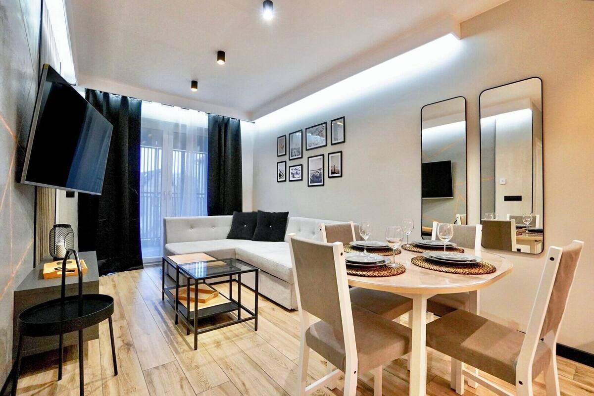 A modern living room with a sofa, coffee table, and dining table set for four.