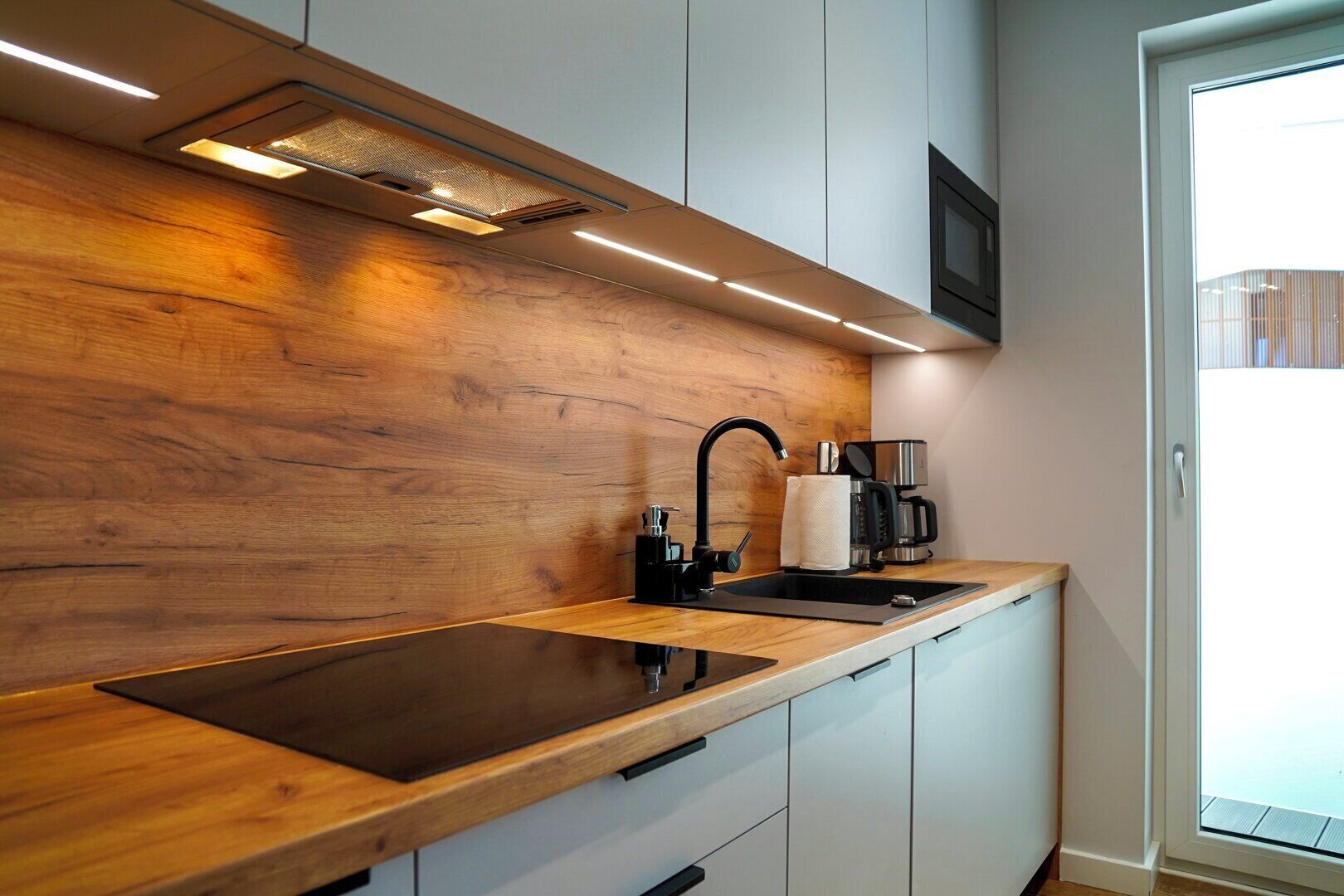 Une cuisine moderne dotée d’un plan de travail en bois, d’un évier encastré et d’une machine à café.