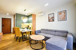 Una sala de estar moderna con un sofá gris, una mesa de centro redonda y una zona de comedor con sillas amarillas y una mesa de madera.