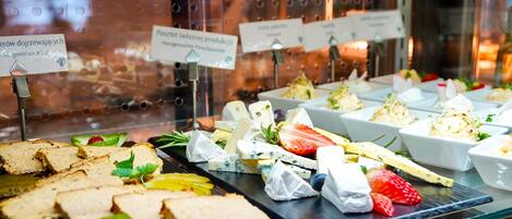 A buffet with various food items including sandwiches, cheese, and fruits.